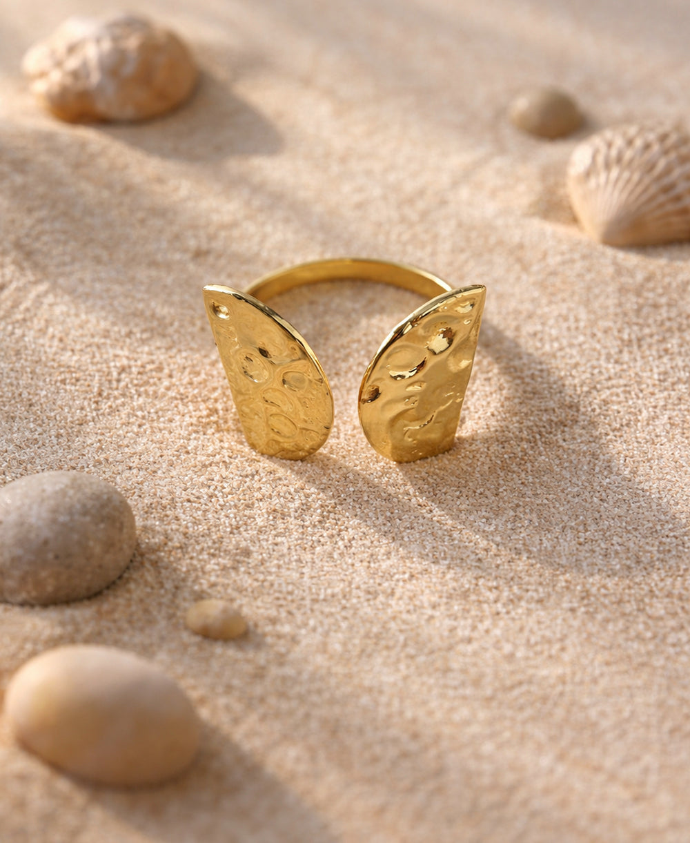 Golden Tide 18K Adjustable Ring with hammered gold texture placed on sand with seashells
