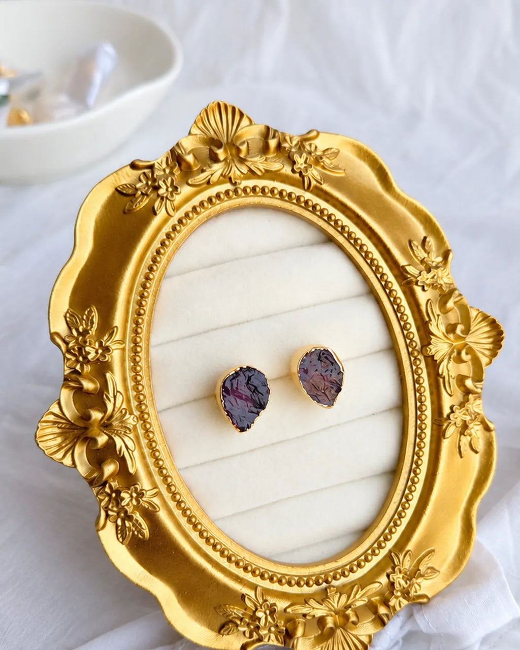 Purple raw gemstone gold stud earrings in ornate gold jewellery display