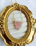 Close-up of pink floral carved triangular pendant on gold-tone chain
