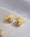 Gold earrings with pearl center on a light background