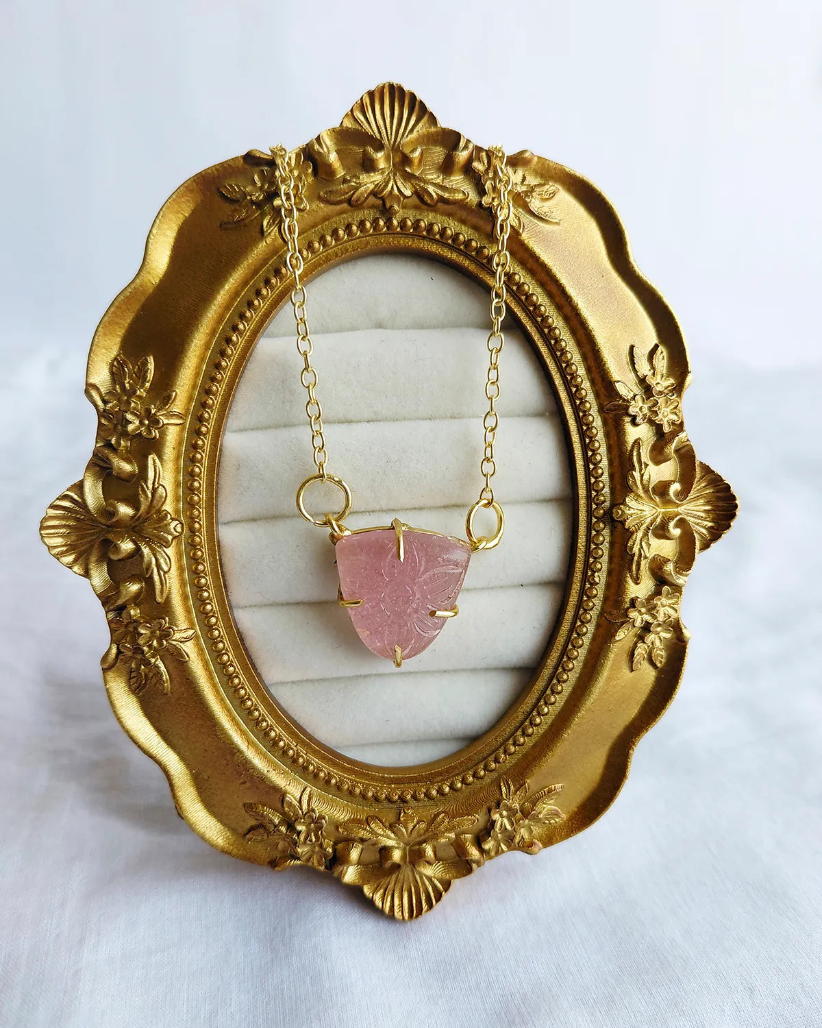 Full view of carved pink pendant necklace on jewellery display
