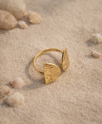 Gold ring with geometric design on a sandy surface with shells