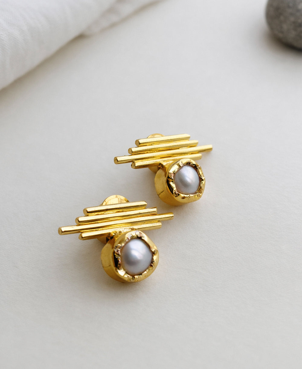 Gold earrings with pearl-like stones on a light background