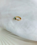 Gold ring with a green gemstone on a white fabric background