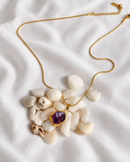 Raw amethyst gold pendant necklace on ivory fabric