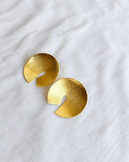 Brushed gold circular disc earrings on white cloth