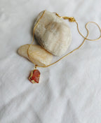 Carnelian gemstone necklace displayed on white fabric with natural stones