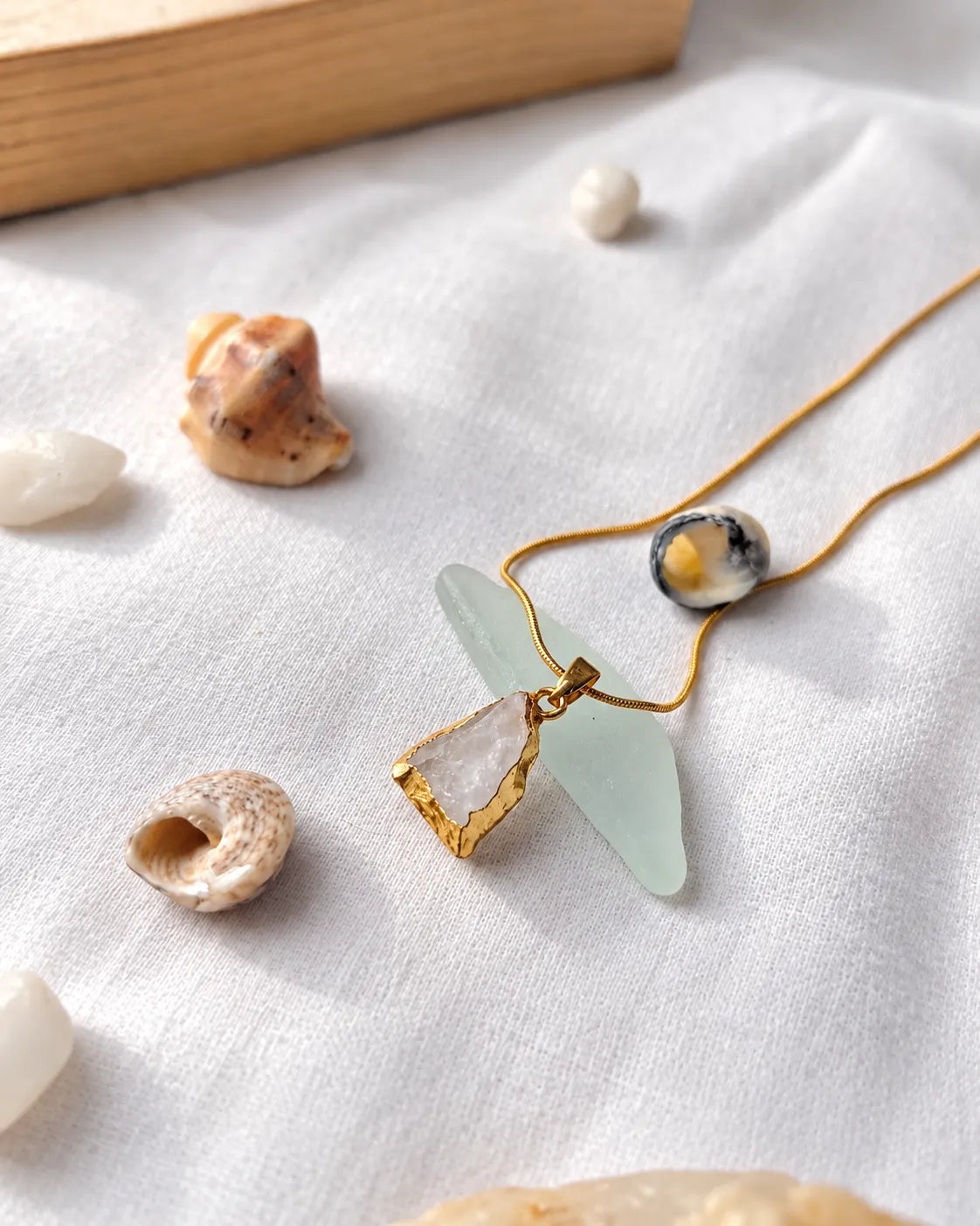 Raw clear quartz gold pendant necklace styled with shells