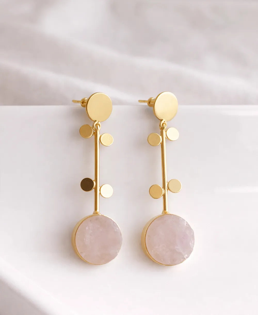 Gold earrings with pink stones on a white background