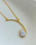 Ivory Arc Howlite 18K Gold Plated Necklace with white teardrop gemstone and curved gold pendant design.