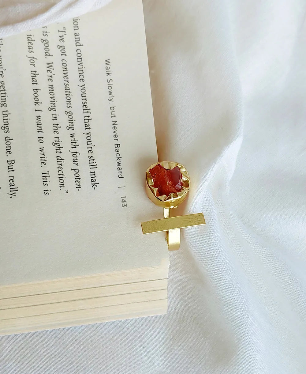 Gold bookmark with a red gemstone on an open book