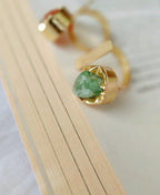 Gold ring with a green gemstone on a light wooden surface