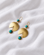 Gold and turquoise drop earrings on ivory fabric