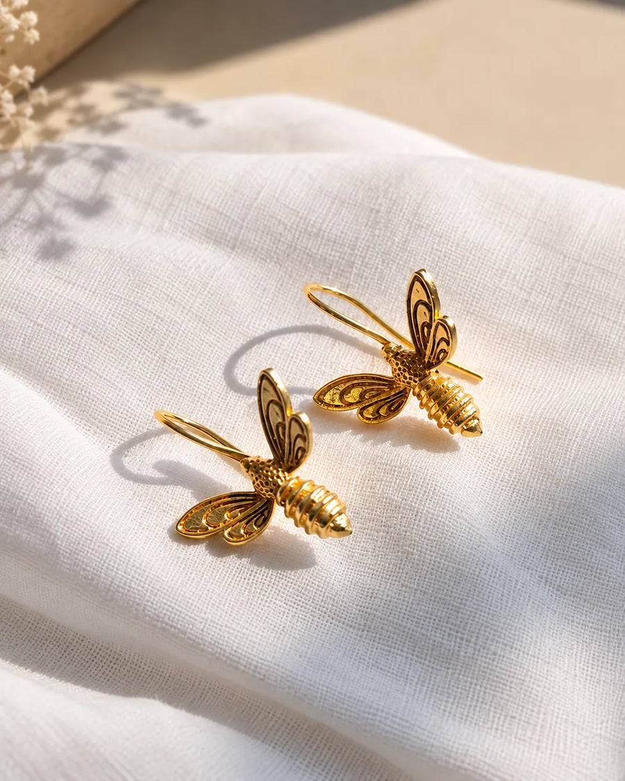 Golden bee earrings on linen