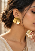 Model wearing brushed gold sculptural disc earrings