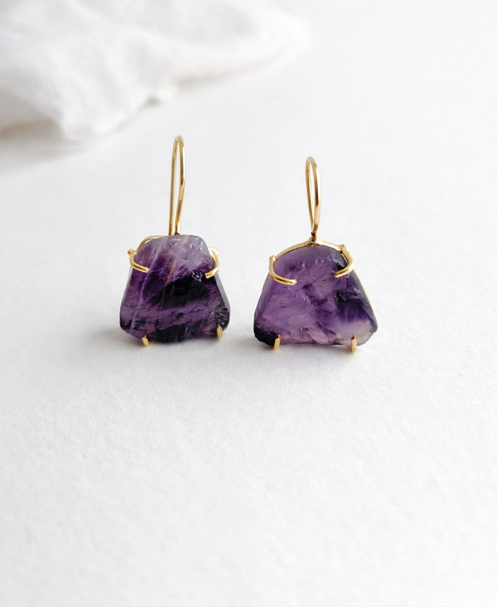 Pair of purple gemstone earrings with gold accents on a white background