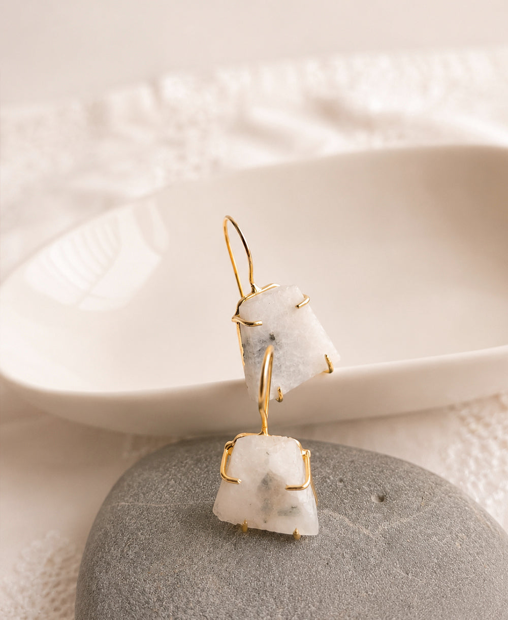 Earring with white stone and gold accents on a textured surface