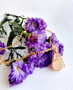Necklace with purple flowers and gold chain on a white background