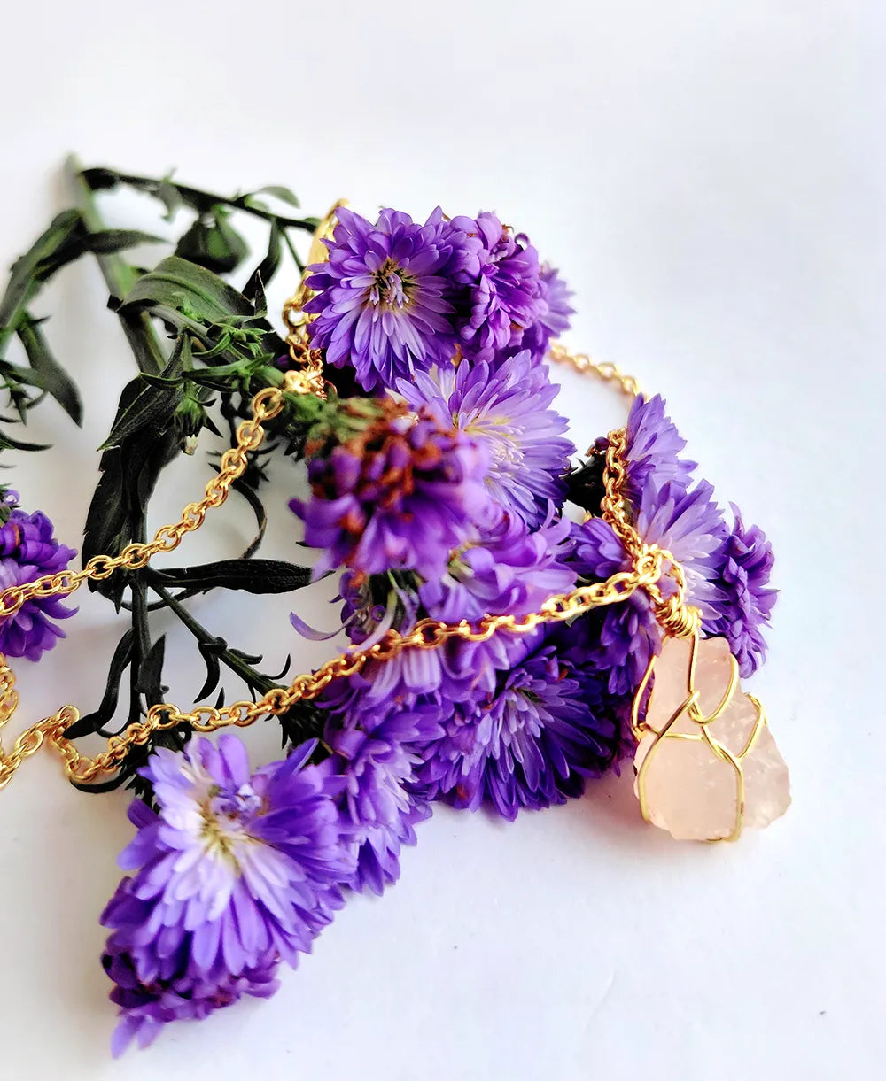 Necklace with purple flowers and gold chain on a white background