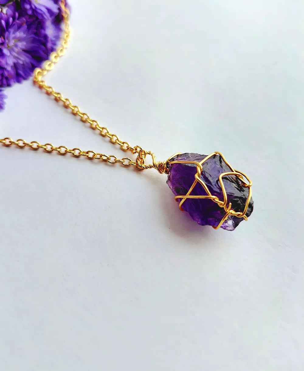 Amethyst necklace with gold wire wrapping on a light background