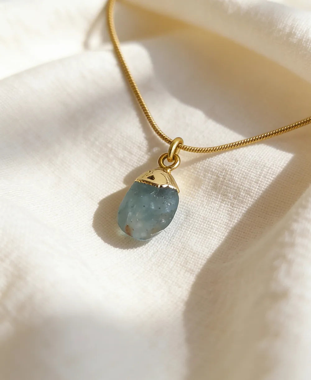 Sea Glass Aquamarine 18K Gold Plated Necklace with natural raw blue gemstone and gold-capped pendant on snake chain.