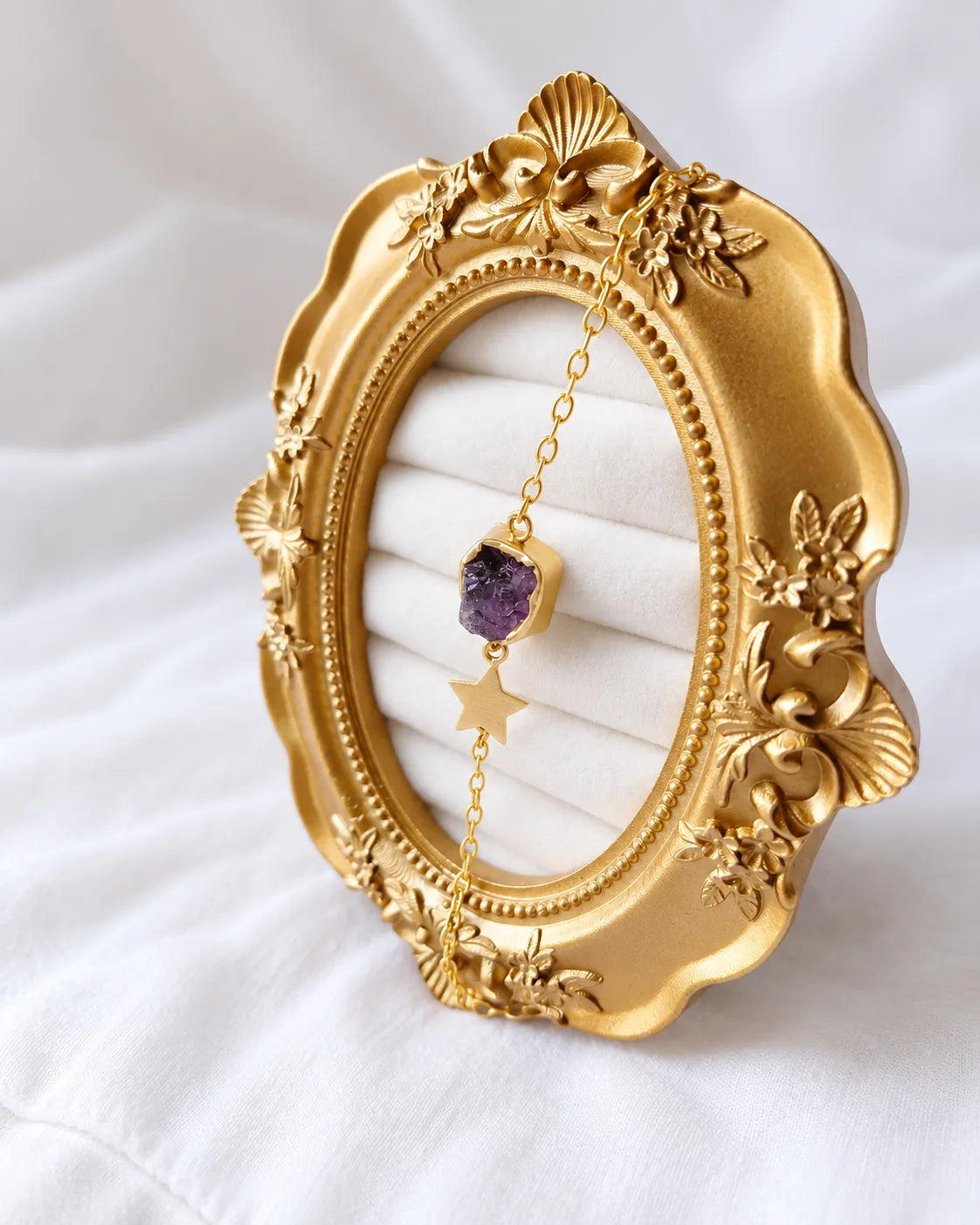 Amethyst star bracelet displayed on ornate gold frame
