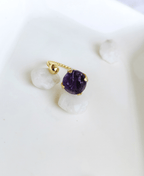 Raw Amethyst gemstone adjustable ring in gold plated finish placed on white stones.