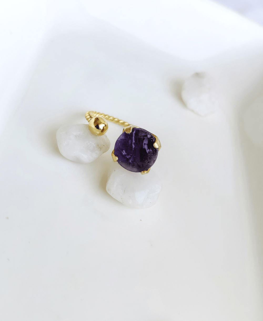 Raw Amethyst gemstone adjustable ring in gold plated finish placed on white stones.
