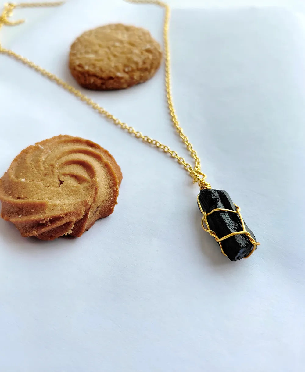 Gold necklace with a black pendant on a white background