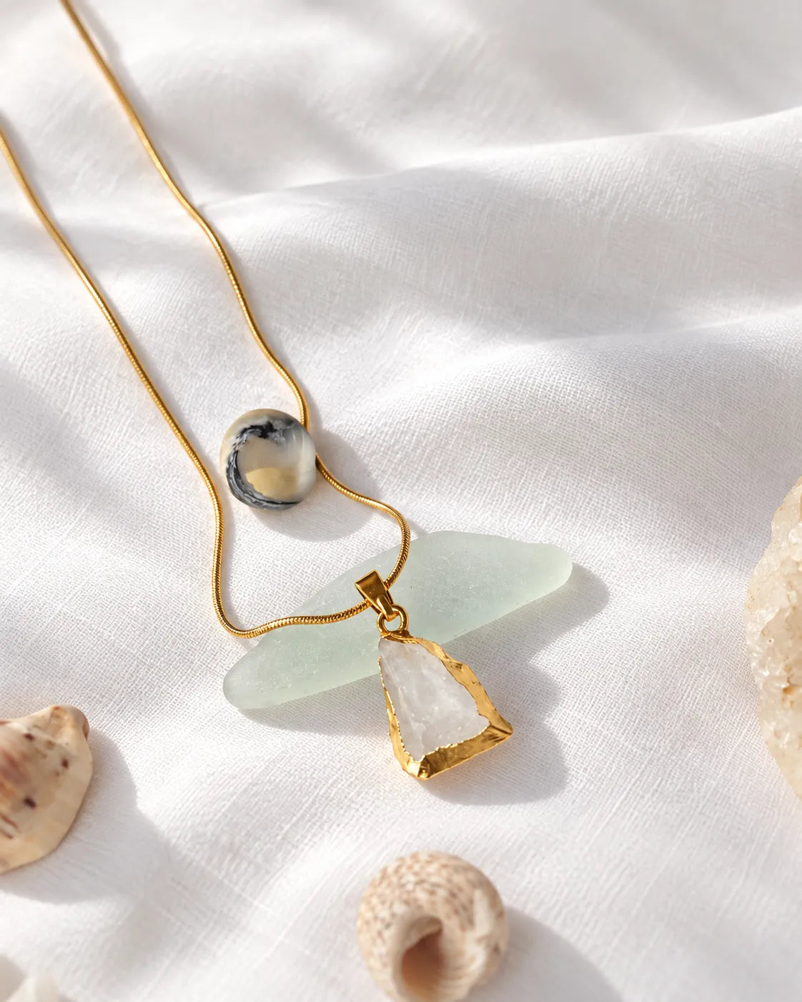 Raw clear quartz gold pendant necklace on linen