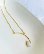 Gold necklace with a teardrop-shaped pendant on a white background