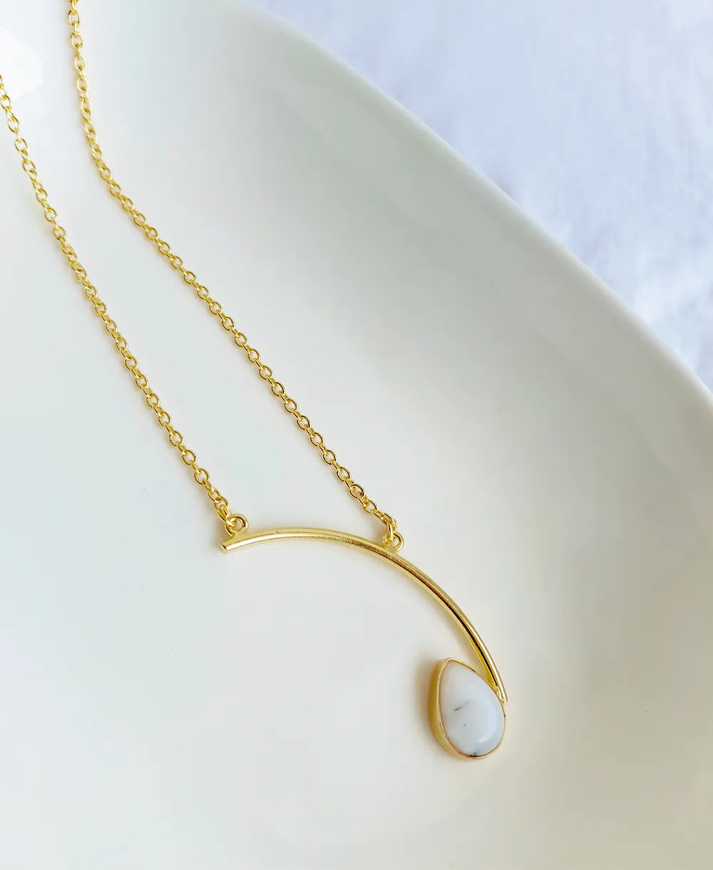 Gold necklace with a teardrop-shaped pendant on a white background