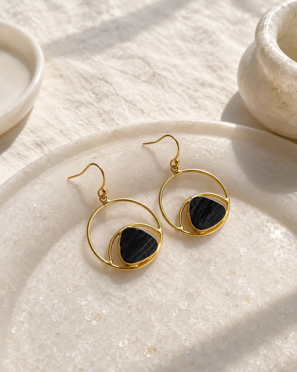 Black stone gold orbit earrings on stone tray