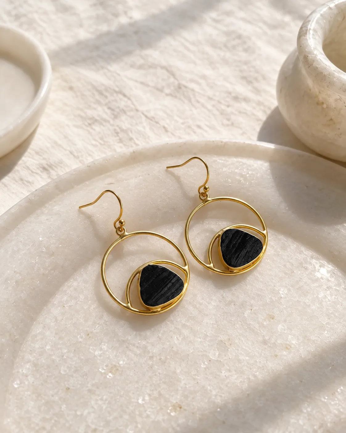 Black stone gold orbit earrings on stone tray