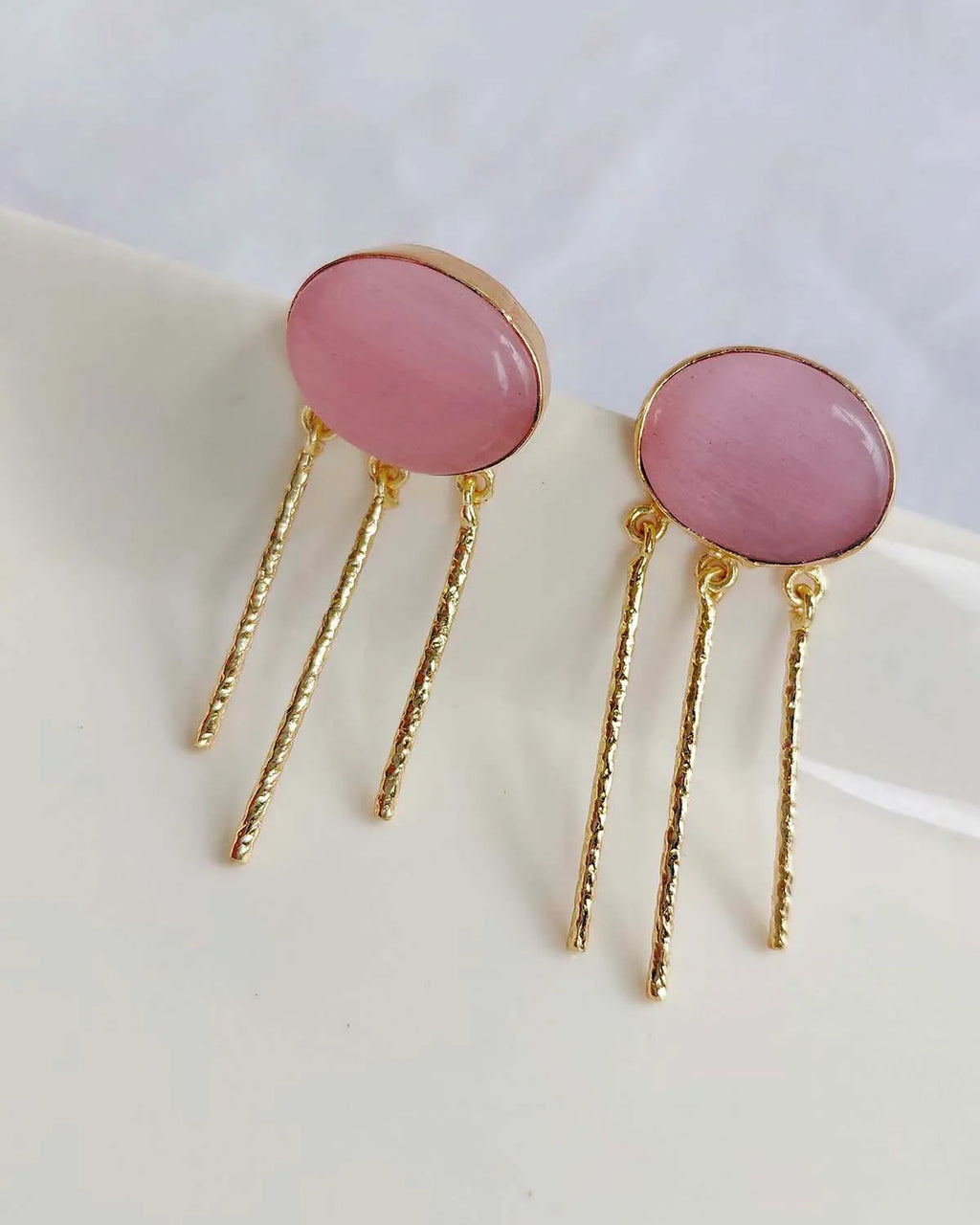 Close-up of blush pink gemstone gold-plated drop earrings
