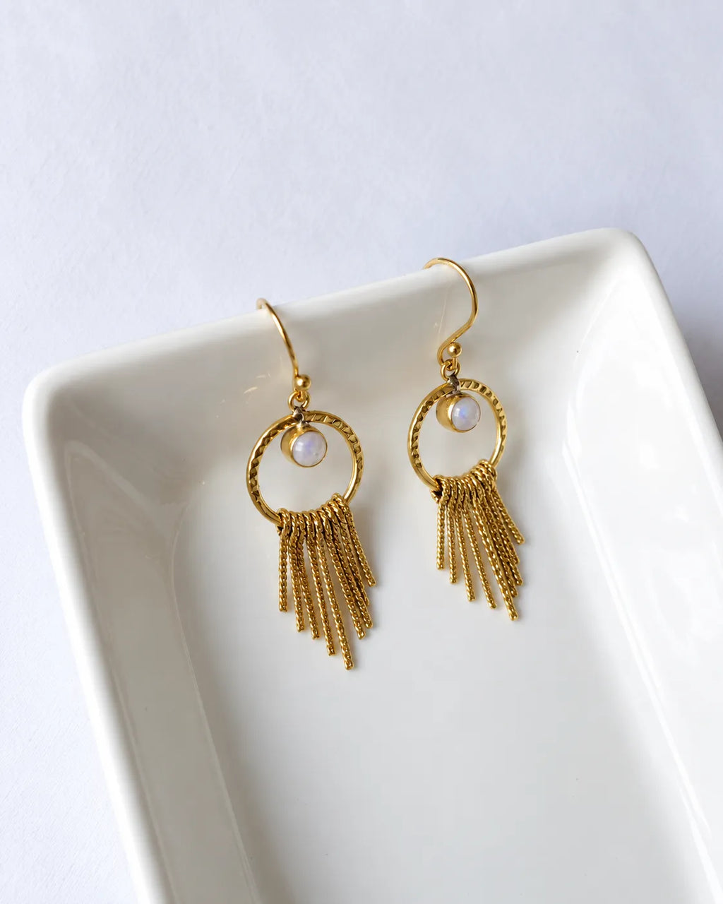 Moonstone gold tassel earrings on ceramic tray