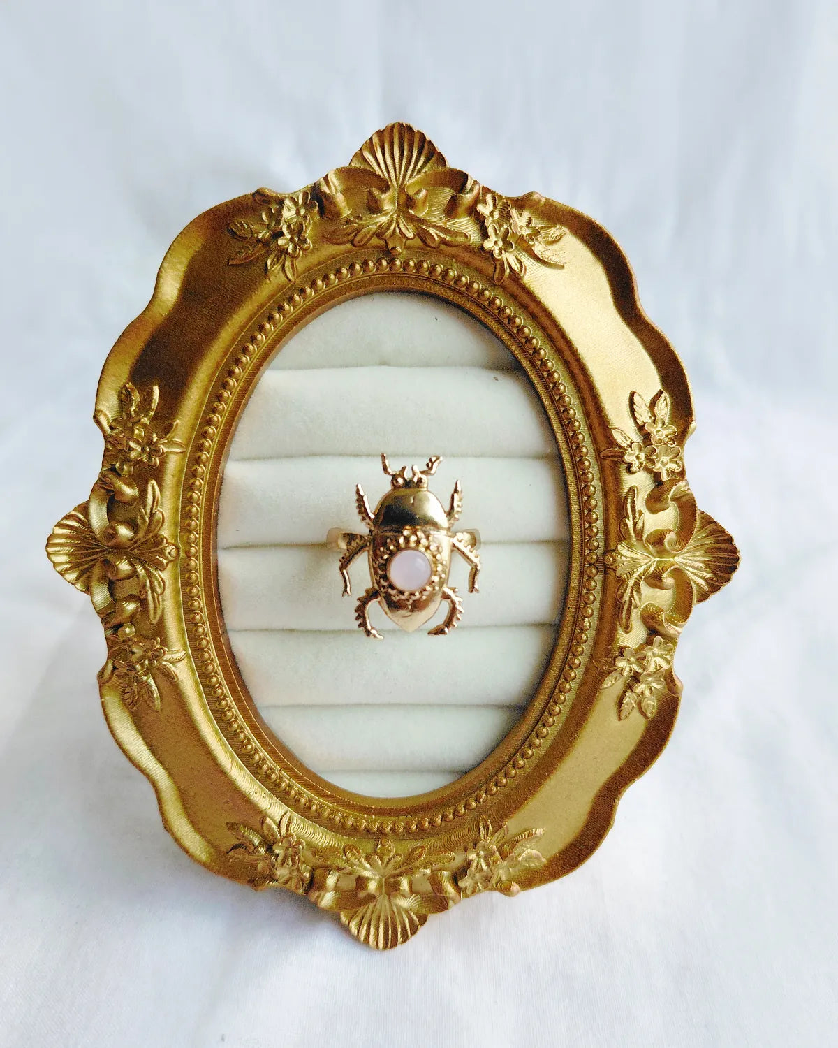 Pink stone scarab gold plated ring front view in ornate gold frame