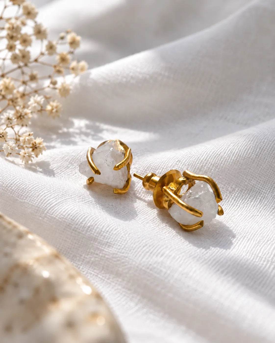 Raw white crystal gold stud earrings on white linen
