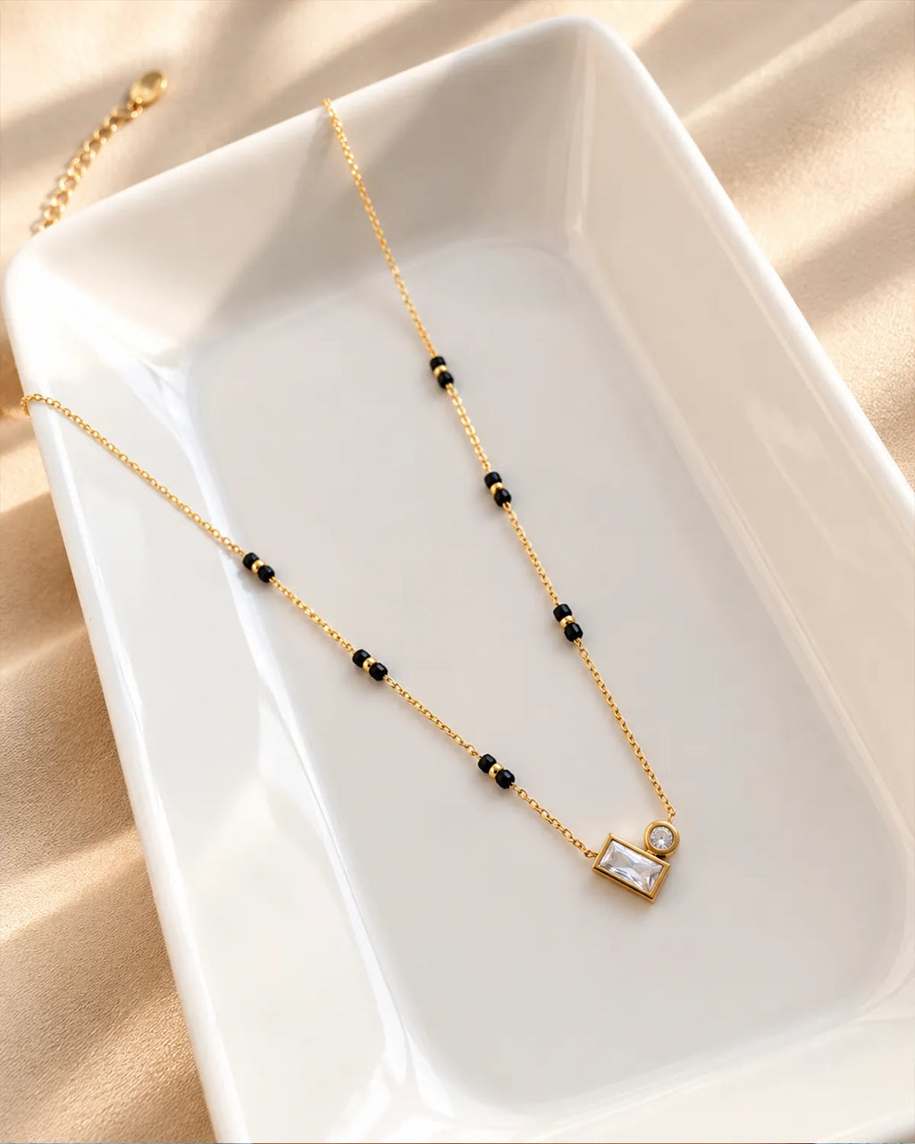 Gold-tone black bead mangalsutra with rectangular and round clear stone duo pendant