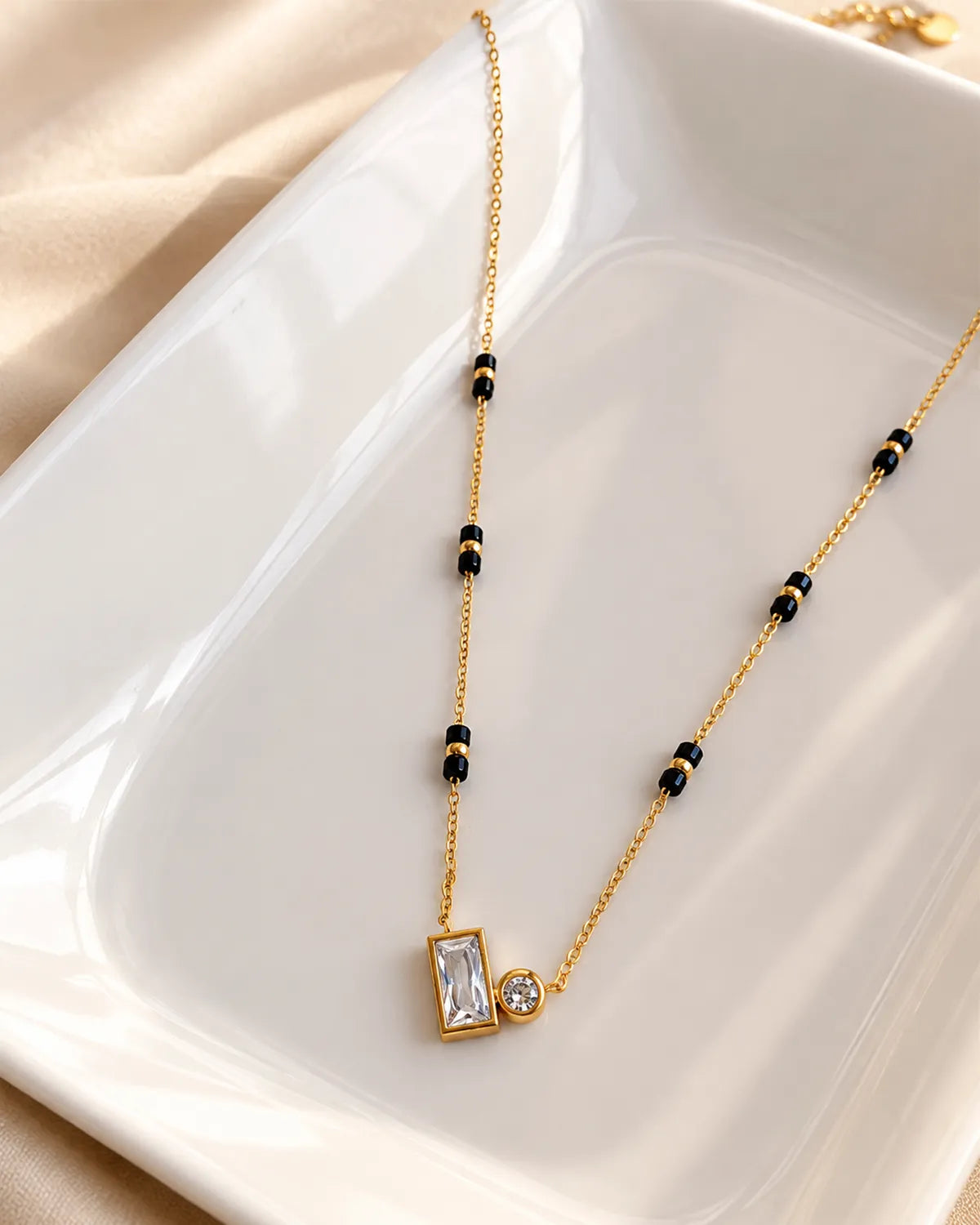 Gold-tone black bead mangalsutra with rectangular and round clear stone duo pendant