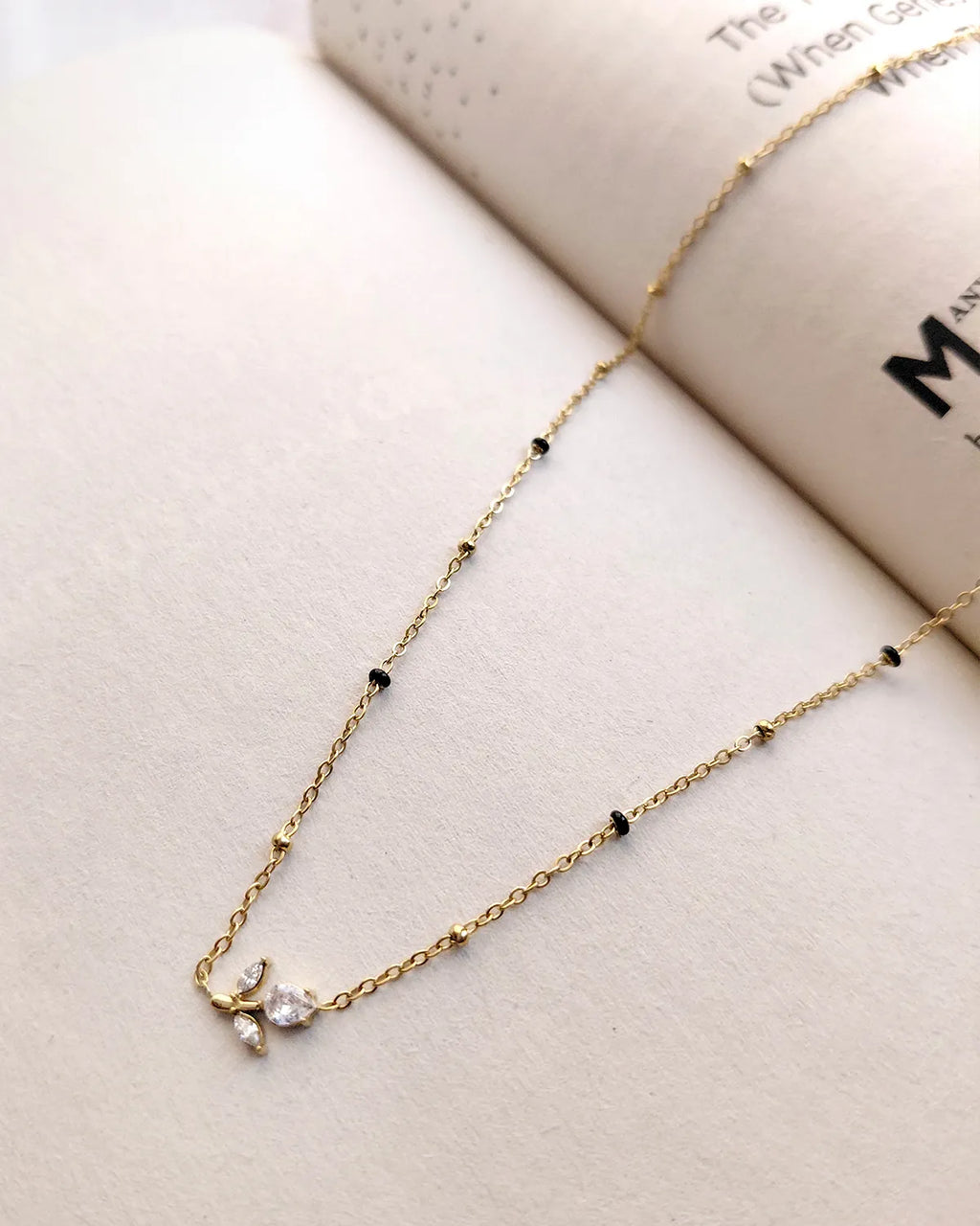 Floral sprig pendant mangalsutra with delicate black beads and gold-tone chain