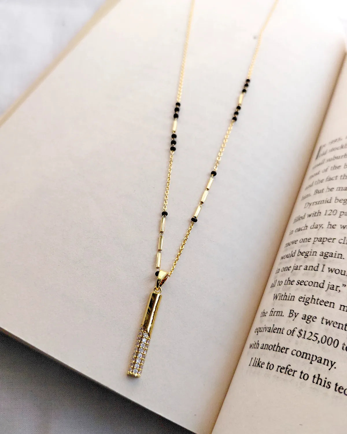 Long vertical gold bar pendant with sparkling clear stones and black bead mangalsutra chain