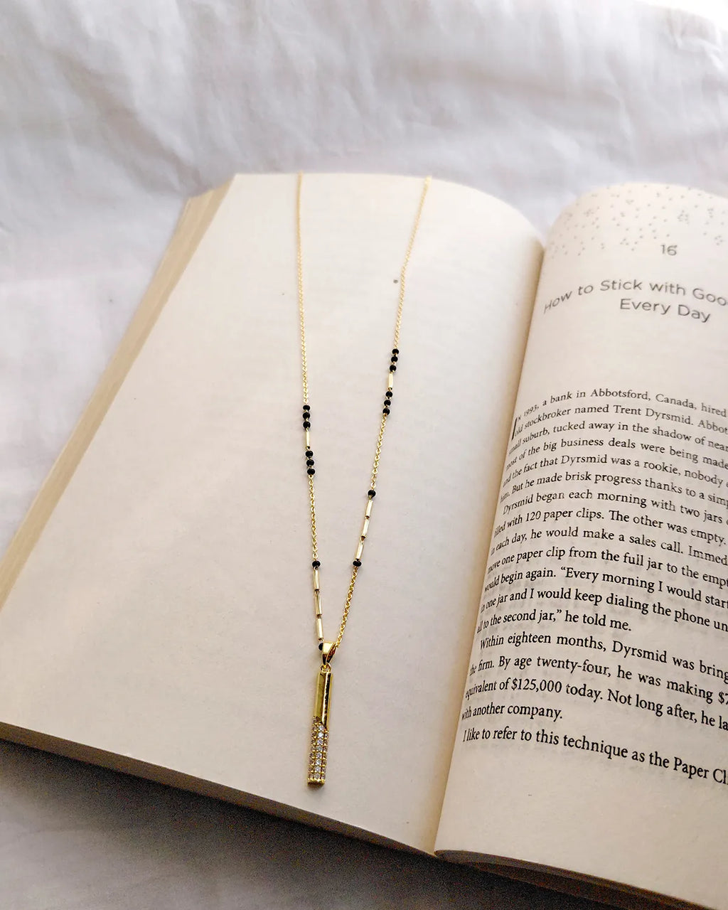 Long vertical gold bar pendant with sparkling clear stones and black bead mangalsutra chain