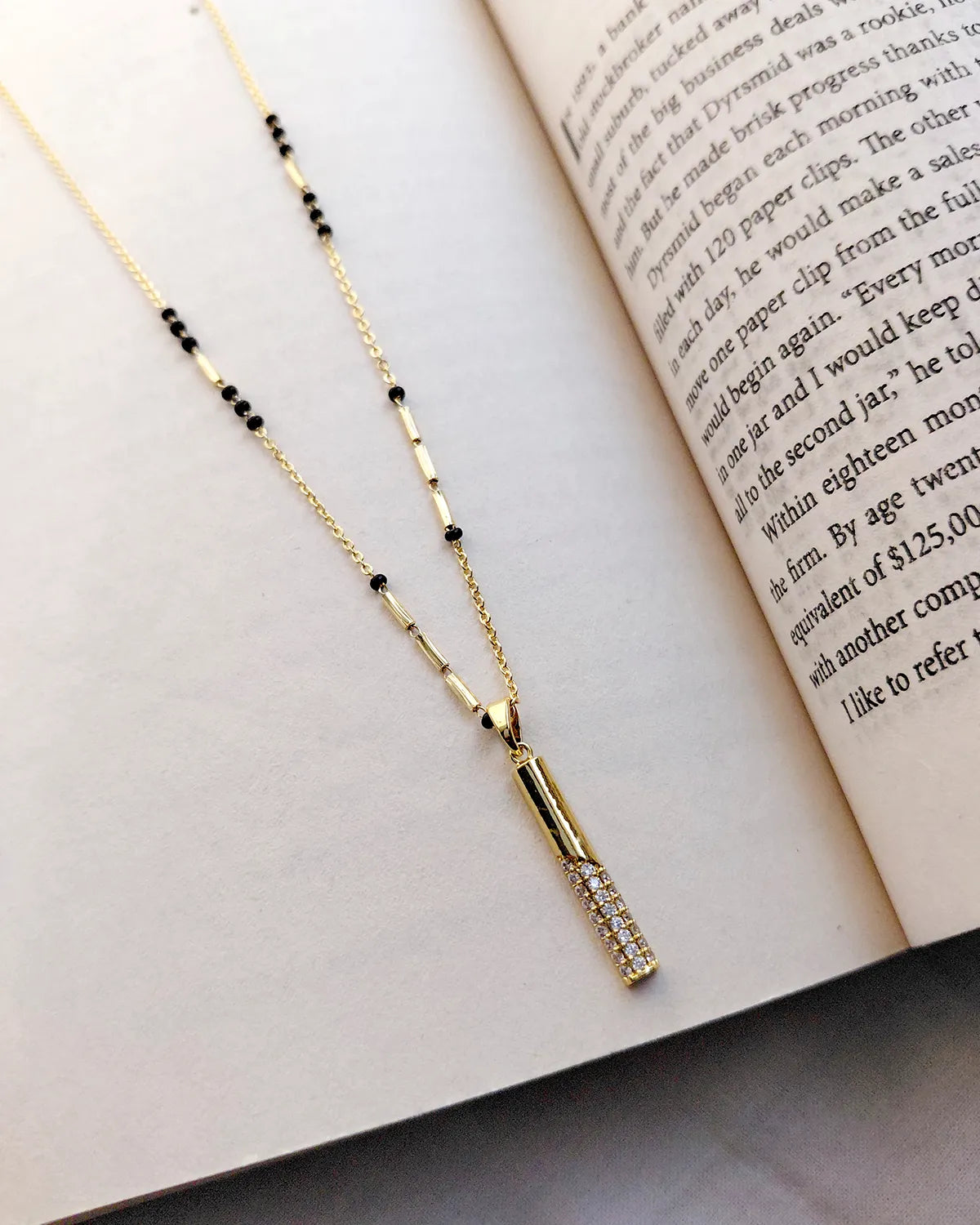 Long vertical gold bar pendant with sparkling clear stones and black bead mangalsutra chain