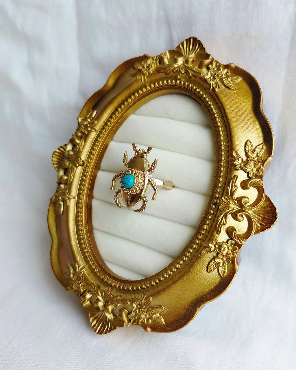 Turquoise blue scarab gold plated ring angled view in ornate gold frame